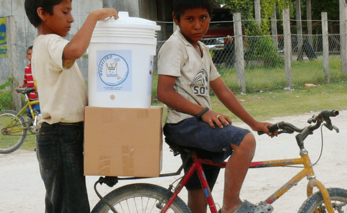 Two young men transport the Ecolfilter on their bicycle as part of the Pure Water Pathways Program, a sustainable initiative by Martsam Travel.