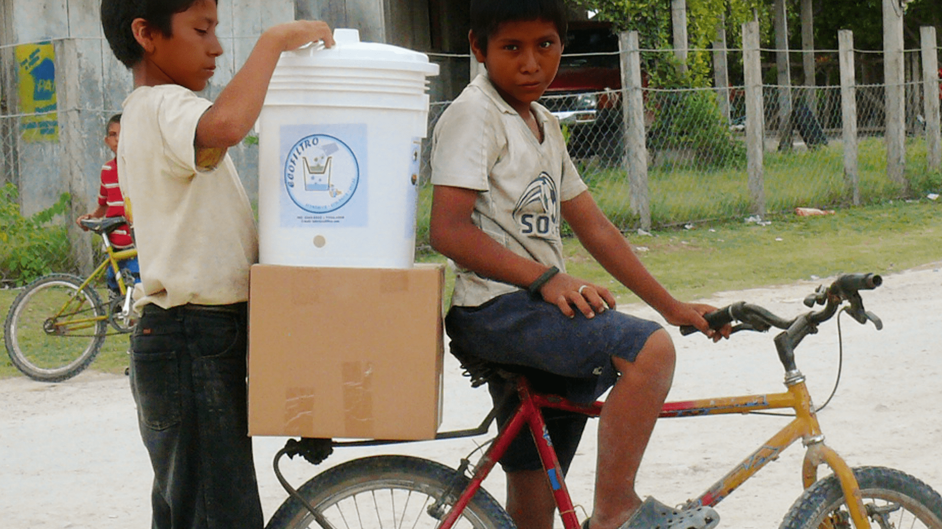 Two young men transport the Ecolfilter on their bicycle as part of the Pure Water Pathways Program, a sustainable initiative by Martsam Travel.