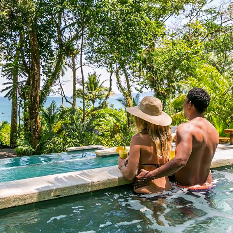 A couple enjoying the swimming pool and tropical drinks during the Costa Rica Tour Package.